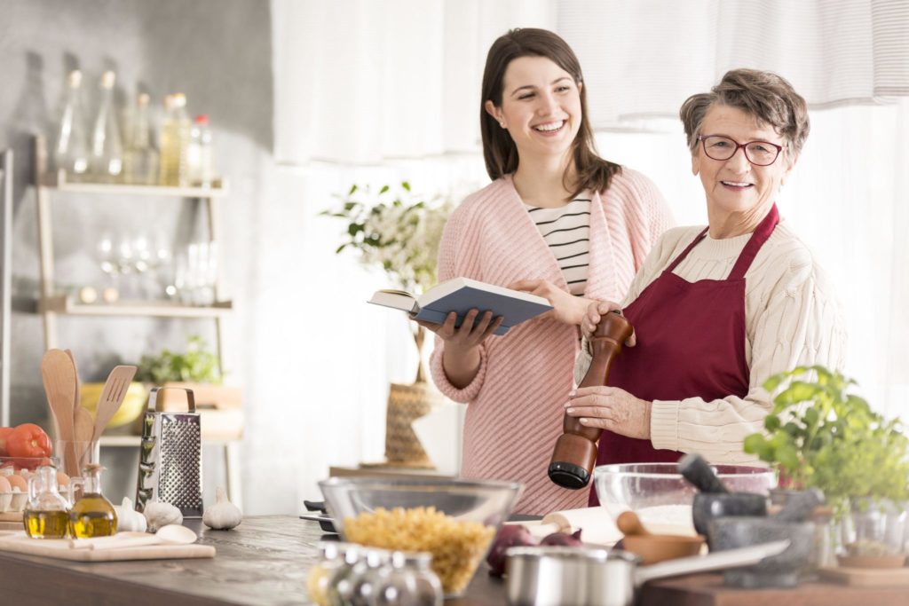 77351596 – happy women standing and cooking in modern kitchen