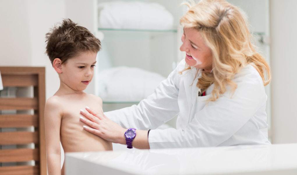 Physical therapist doing medical exam with little boy Jak przeciwdziałać wadom postawy u dzieci?